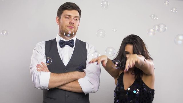 happy woman and bored man at party with bubbles