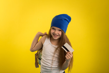 Beautiful caucasian girl posing on yellow isolated background in studio holding in hands a credit card