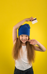 Beautiful caucasian girl posing on yellow isolated background in studio holding in hands a credit card