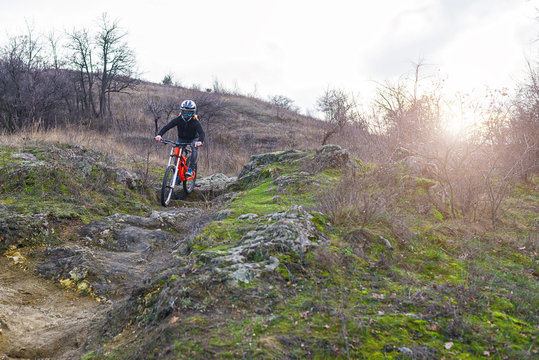 Cyclist riding a mountain bike on rocks, downhill.