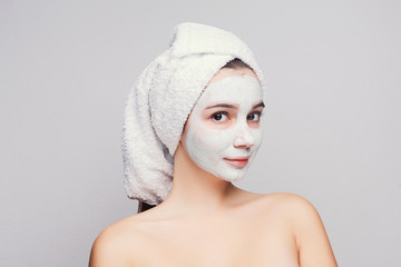 Beautiful girl with applied clay mask at white background