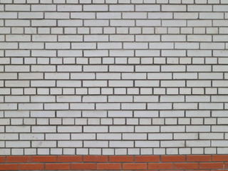 a wall of white brick with a strip of red brick