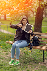 Young girl in the park with a tablet in hand.