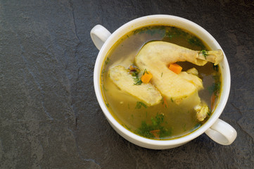 Chicken soup with vegetables on a black background.