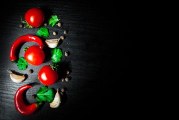 Garlic, red chili peppers, tomato on dark wooden background with copy space. top view