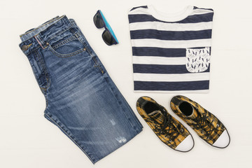 Top view fashion trendy look of kids clothes on white wooden background. Kids fashion.