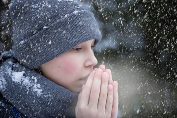 A boy warms his hands from the cold in winter