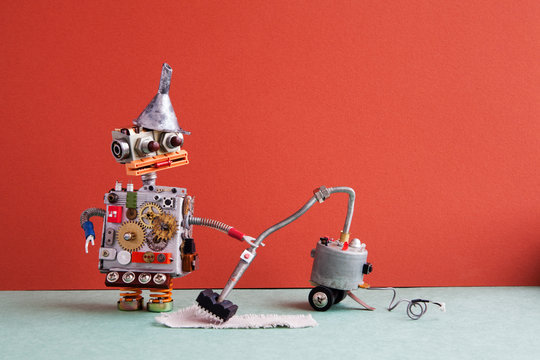 Robot vacuum cleaner machine service. Funny robotic toy metal funnel hopper, cogs wheels gears metallic body, cleaning carpet process, red wall room interior.