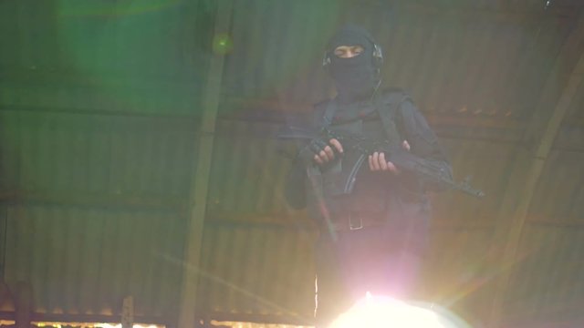 A SWAT member in black gear holds a rifle with both hands. 