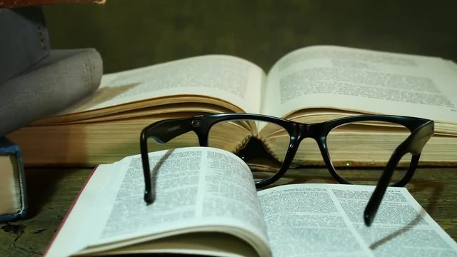 Open Bible with Glasses on the Old Table. Zoom in.