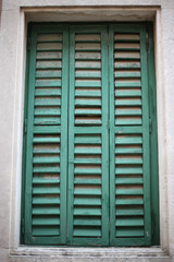 The window opening on the facade of the building is covered with old wooden blinds