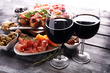 Italian antipasti wine snacks set. Cheese variety, Mediterranean olives, pickles, Prosciutto di Parma, tomatoes, artichokes and wine in glasses