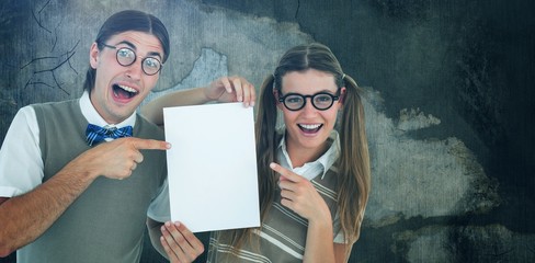 Composite image of geeky hipsters pointing at poster 