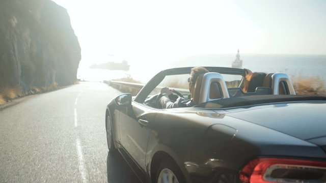 Cheerful couple on the vacation journey by a convertible