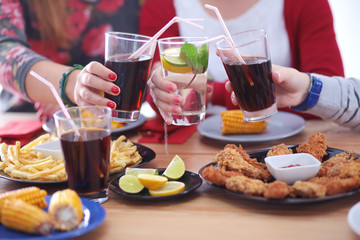 Top view of group of people having dinner together while sitting at wooden table. Food on the table. People eat fast food.