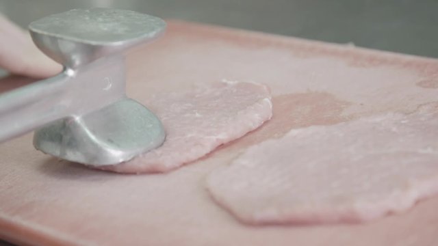 Close up, chef tenderizes raw pork