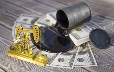 Concept of gold oil drilling pump, spilled oil from barrel on dollar banknote money. Business idea