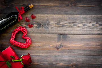 Celebrate Valentine's day. Wine, red rose, heart sign, gift box on dark wooden background top view copy space