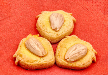 Three cookies or biscuits with almond on red background. HDR effect.