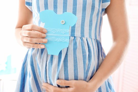 Pregnant woman holding card near belly, closeup - Powered by Adobe