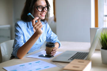 Obraz premium Young woman sitting in office table, looking at laptop computer screen . Young woman