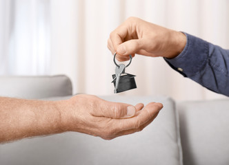 Real estate agent giving house key to senior man indoors