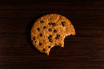 Bitten chocolate chip cookie on a dark wooden table