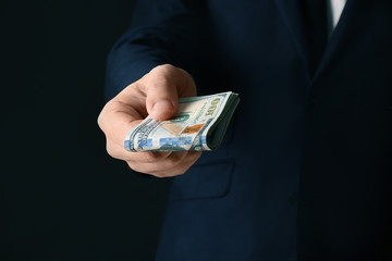 Businessman holding bribe on black background