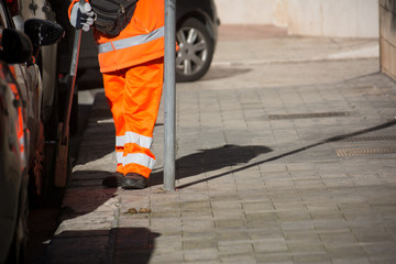 Horizontal View of a Dustman Cleaning the Street With a Mop Wearing an Orange Uniform