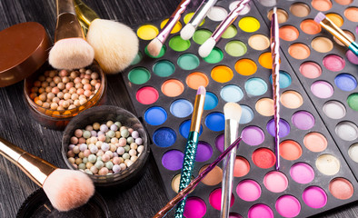Make-up brushes laying on colorful cosmetic palette. Close up.