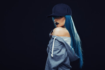 Young woman with cyan color hair in hoodie and cap