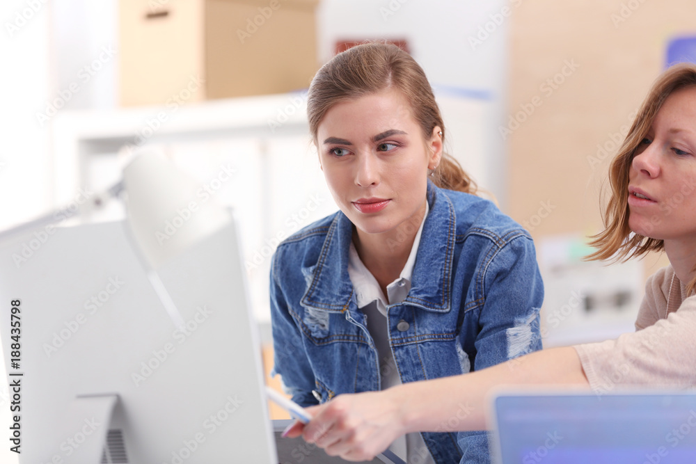 Wall mural two young woman standing near desk with instruments, plan and laptop.