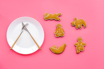 Sport and healthy diet for slimming. Plate, measuring tape and cookies in shape of yoga asans on pink background top view