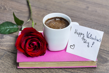 coffee cup with red rose and valentine's handwritten message card on a book