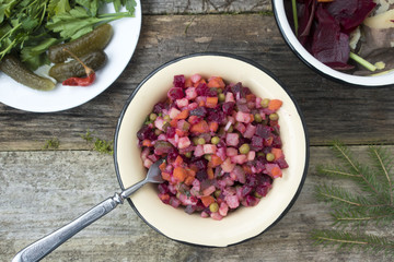 Vinaigrette is located on a wooden table, as well as pickled cucumbers and greens and cleaning leftover from the preparation of vinaigrette.