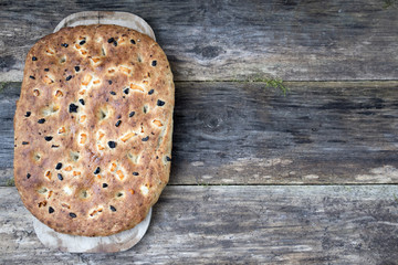 Traditional Italian focaccia homemade bread with tomatoes and olives, on a wooden background and copy space.