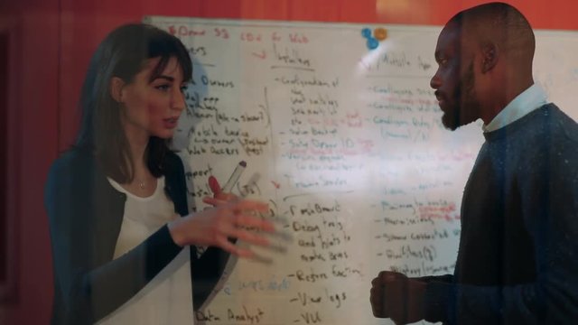 Young girl with beautiful eyes telling something to nice guy. Teacher explaining grammatical rules to student at Foreign Language Study Center. Close-up.
