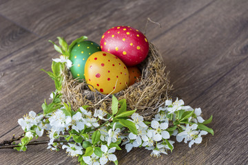 Easter Eggs with in real nest with cherry blossoms on a  wooden background. Easter decoration 