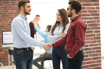 Smiling businessman shaking hands with colleague in office.