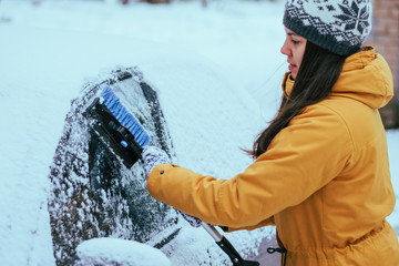 young woman clean car after snow storm