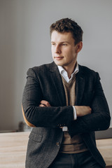 Portrait of a handsome charismatic man in a formal stylish suit who looks out the window