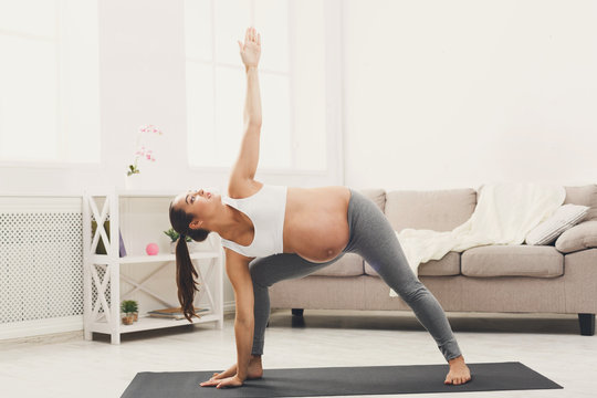 Happy pregnant woman training yoga at home