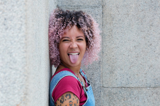 Punkgirl mit rosa Haaren zeigt Zunge