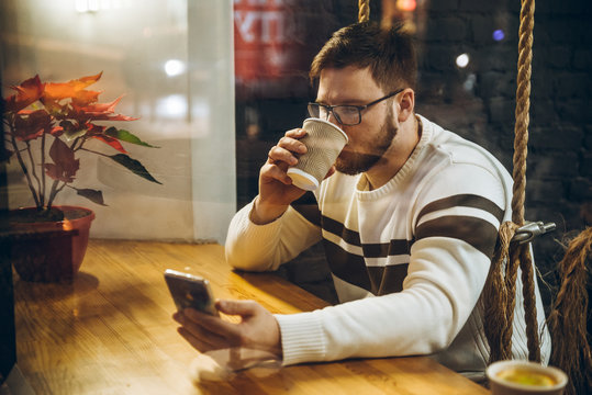 man drink tea and check his phone