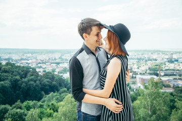 Fototapeta premium couple standing on the hill hugging and looking on city view
