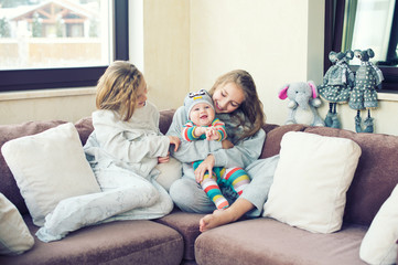 Beautiful toddler girl kissing her little brother at home, laughing and embracing with love and care