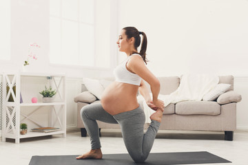 Obraz premium Happy pregnant woman training yoga at home