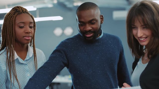 Young African man with beard demonstrating report to two colleagues. Young people working in modern office. Indoors. Close-up.