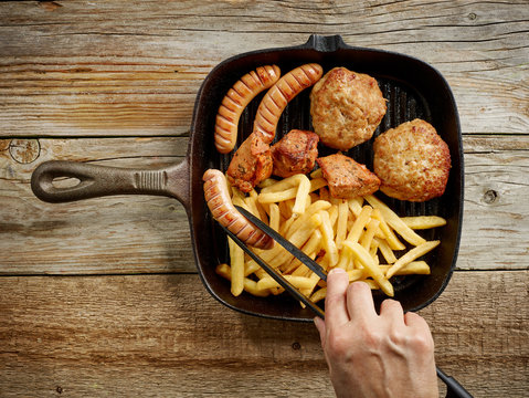 meat sausages and fried potatoes on cast iron pan
