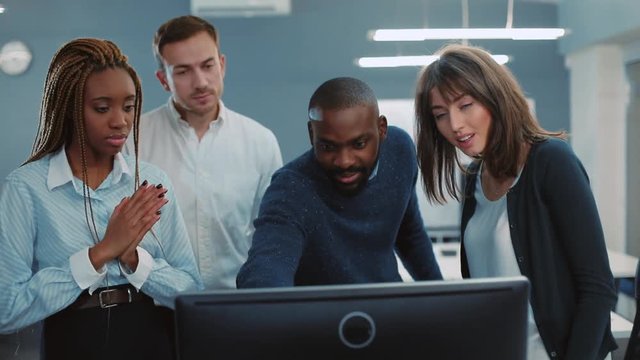 Four office workers watching presentation prepared by one of colleagues. Young people clapping hands. Chief approving project and patting on shoulder of employee.